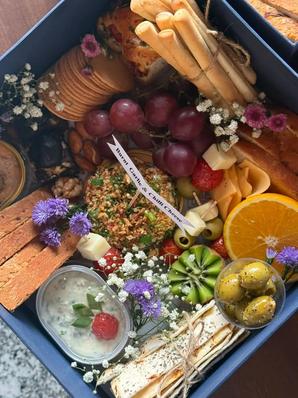 Grazing box with signature burnt garlic and chilli cheese, olives, grapes and breadsticks by Simply Sweet Udaipur