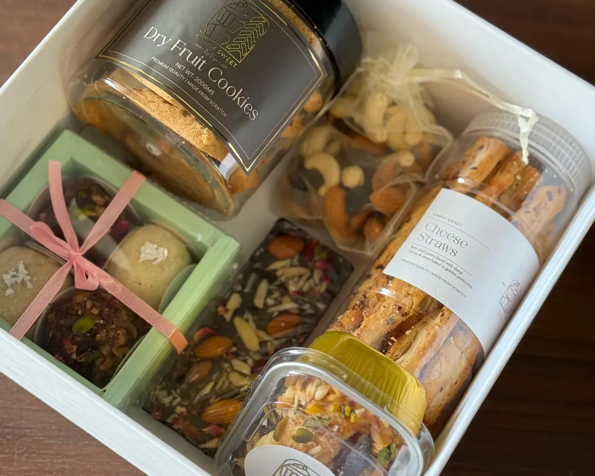 Curated gift hamper box with dry fruit cookies, cheese straws, nuts and mithai by Simply Sweet Udaipur