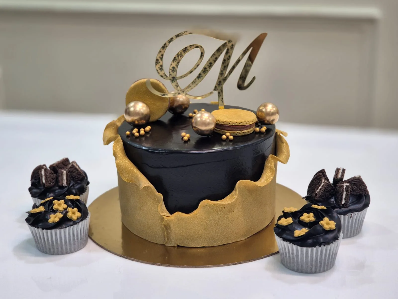 Eggless black and gold drip cake with cupcakes by Simply Sweet Udaipur