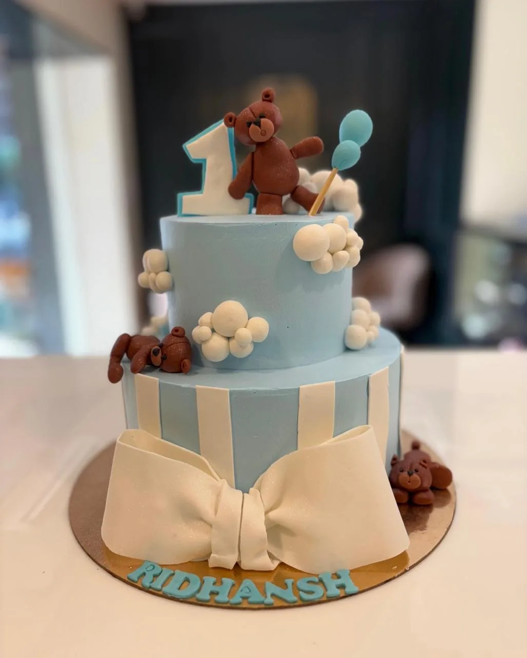 Eggless two-tier teddy bear first birthday cake with blue stripes and fondant bow by Simply Sweet Udaipur