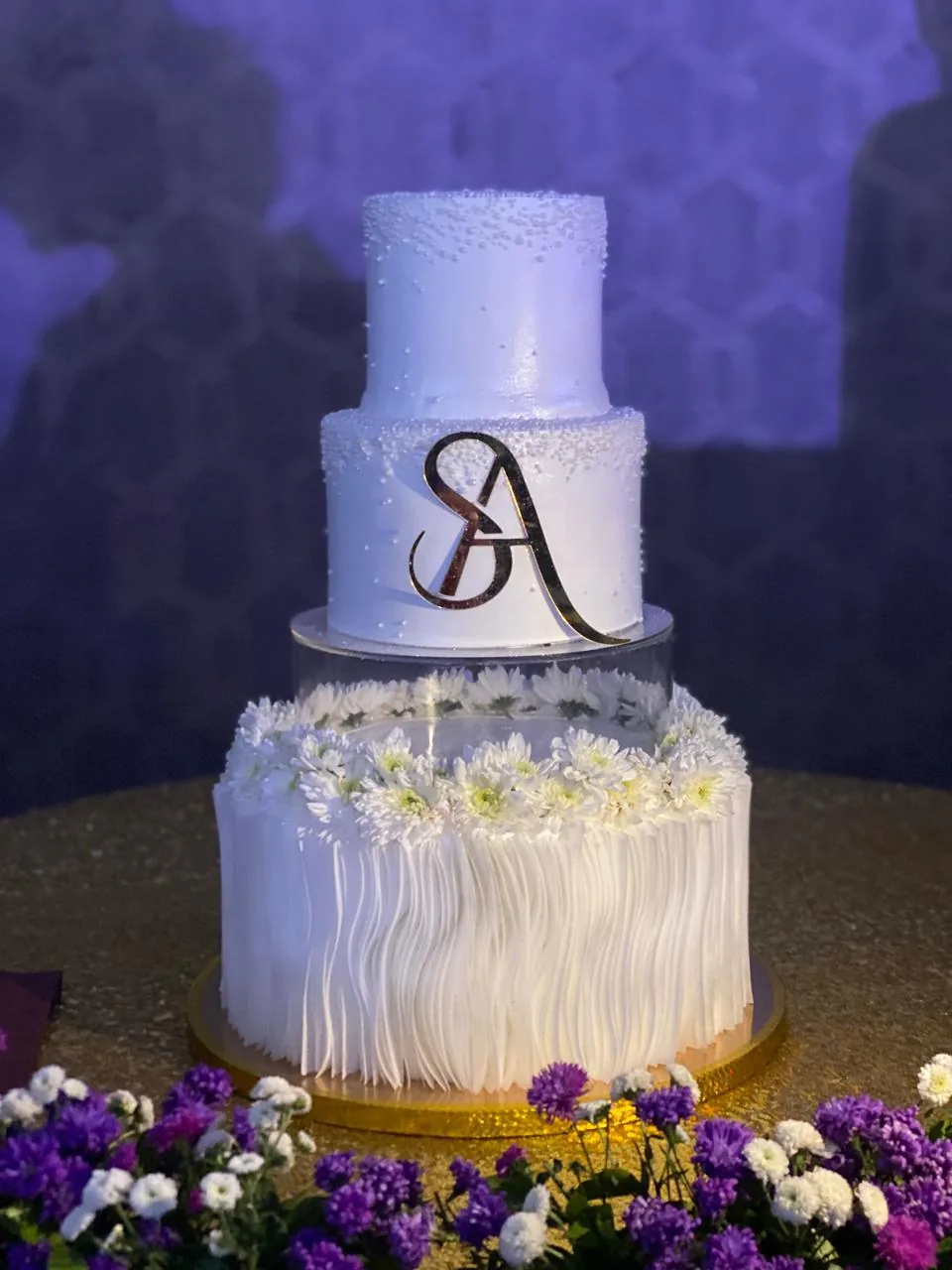 Three tier fringe textured wedding cake with fresh florals and monogram topper by Simply Sweet Udaipur