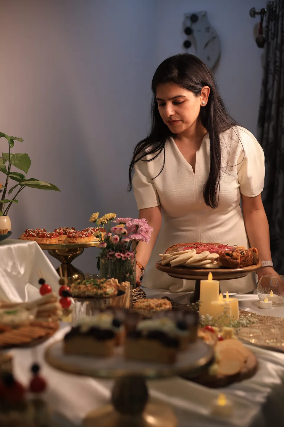 Diya, founder of Simply Sweet, styling a grazing table in Udaipur with savoury platters, fresh flowers and candlelight