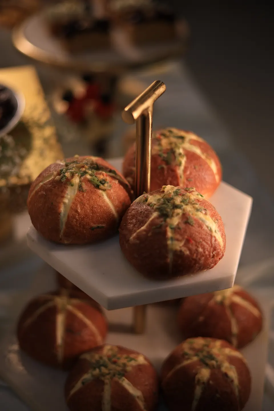 Korean-style cream cheese garlic buns on a marble and gold tiered stand at a Simply Sweet grazing table in Udaipur