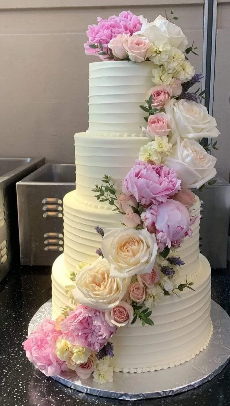 Four-tier buttercream wedding cake with cascading peonies and roses by Simply Sweet Udaipur